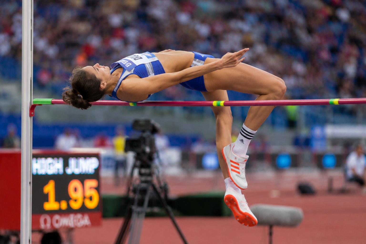 Atleta impegnata nel salto in alto durante una competizione di atletica con l'attenzione rivolta esclusivamente alla tecnica del gesto sportivo.