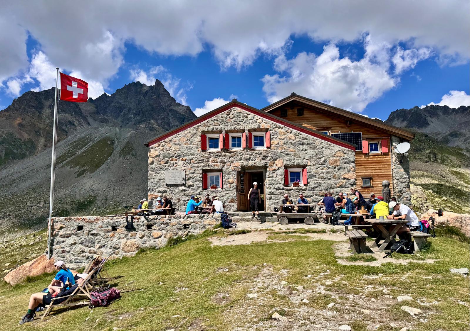 Capanna d’Es-cha a 2594 metri sul passo dell’Albula, con le caratteristiche imposte rosse e le montagne dell’Engadina sullo sfondo.